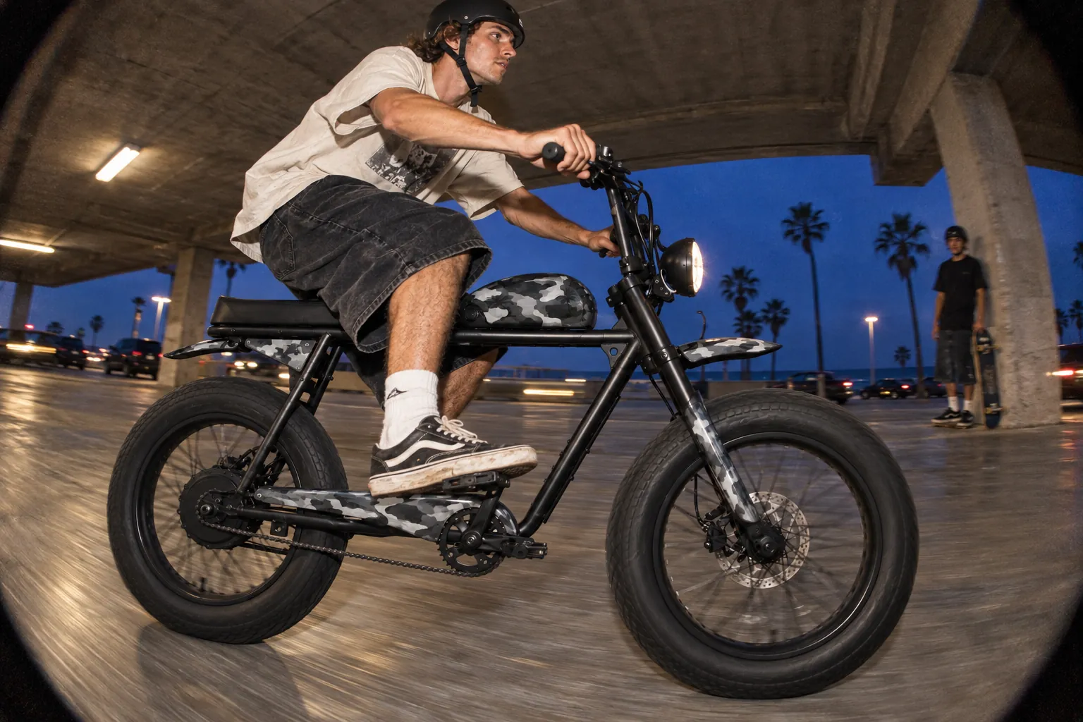 Rider on a black camo Super73 S2 in a parking structure at dusk